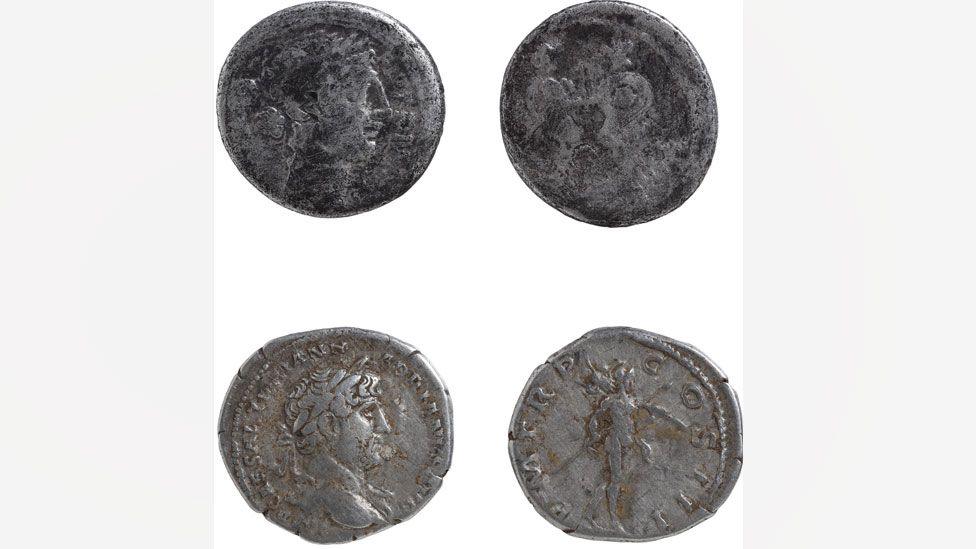 The front and back of two silver Roman coins. The one on the top is the oldest and has been worn almost smooth. A man's face wearing laurel leaves in profile can be seen, while facing it its back is so smooth the pattern lacks definition. The one below shows the emperor Hadrian in profile. Facing it is the reverse showing the god Mars, wearing a helmet and holding a spear.