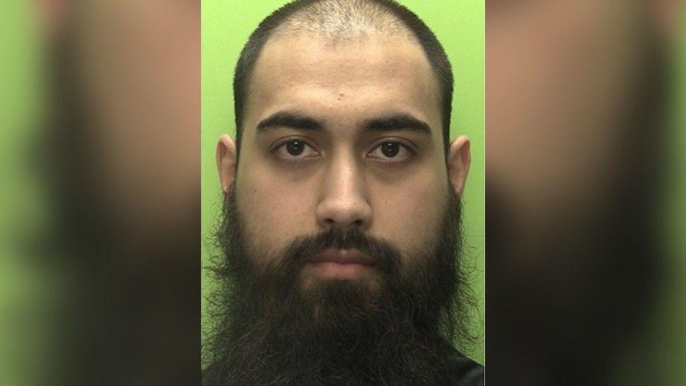 Mugshot of Zakariya Navid who has a shaved head and big beard