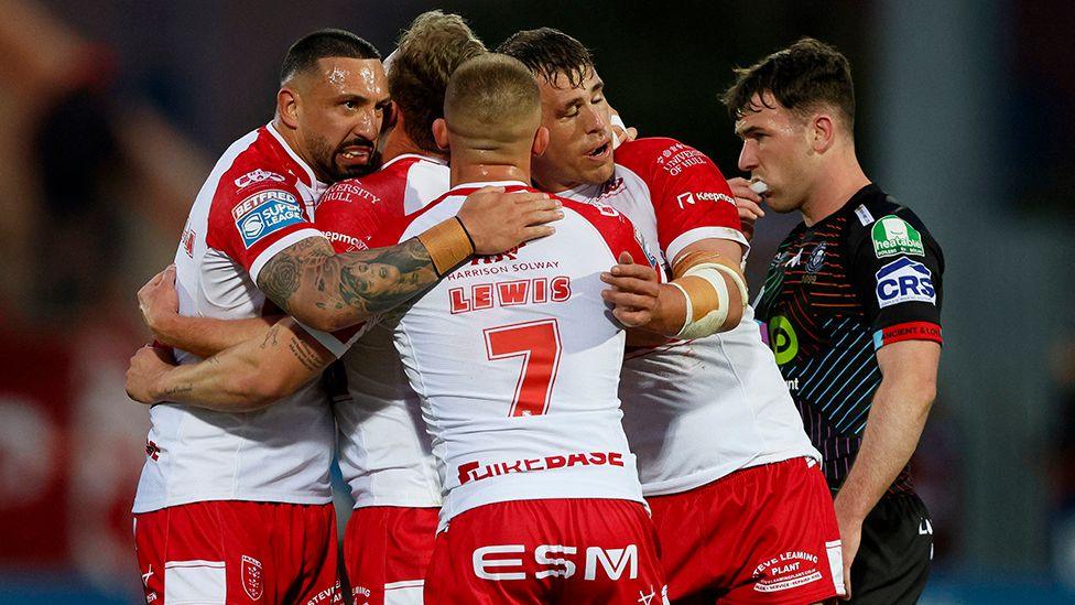 Hull Kingston Rovers players hug after scoring a try against Wigan