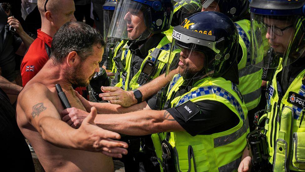 Riot police pushing a protester back