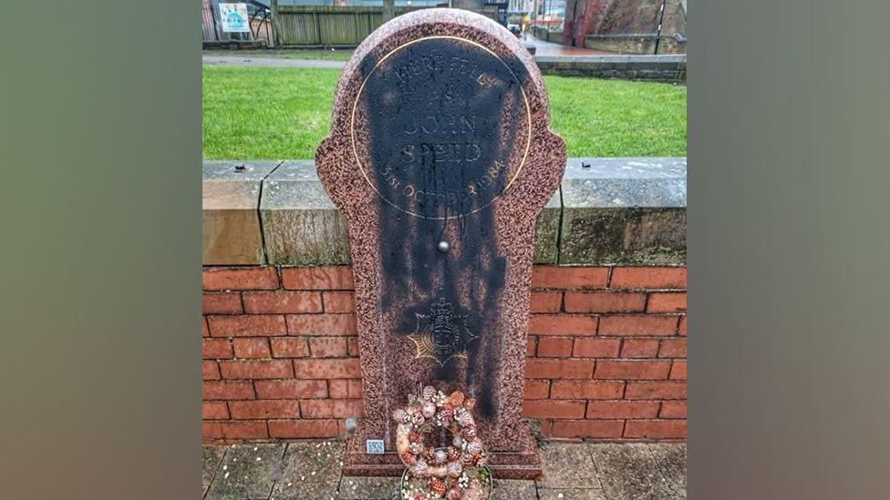 The memorial stone to Sgt John Speed showing black paint sprayed on the stone. 