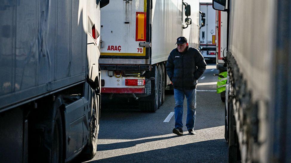 A trucker walks between trucks at a border crossing between Bulgaria and Romania