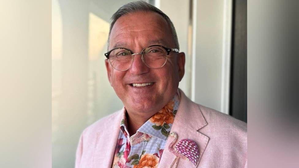 Phil Lewis in a colourful suit smiling at the camera