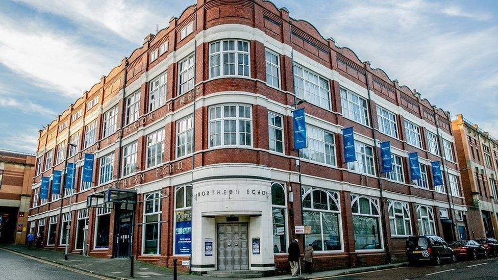 The former Northern Echo building in Darlington. The building's frontage curves around the building on to two streets. There are many glass windows spread across the building's three floors. The entrance is on the corner of the building and is surrounded by white brick.