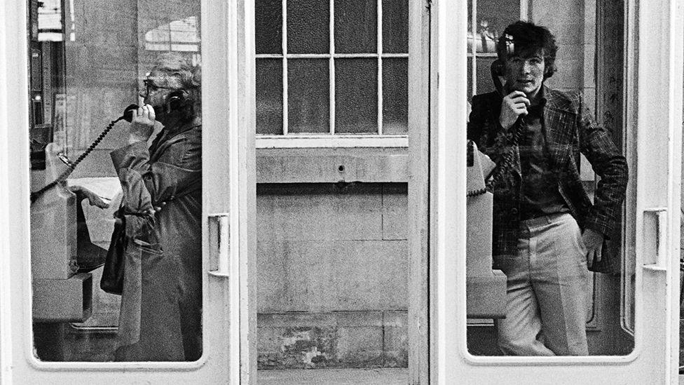 Two people in phone boxes