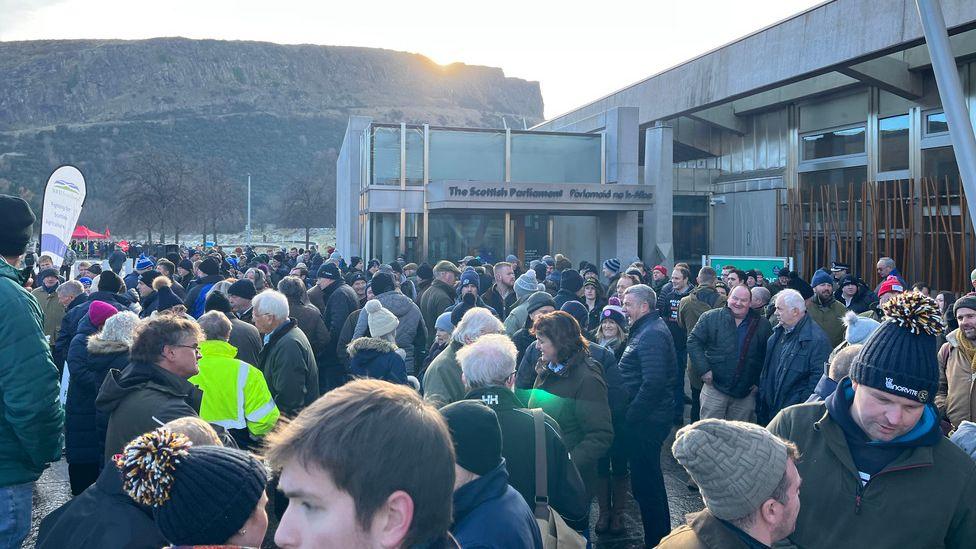 A large crowd of farmers gathered outside the Scottish Parliament near the public entrance to the building.