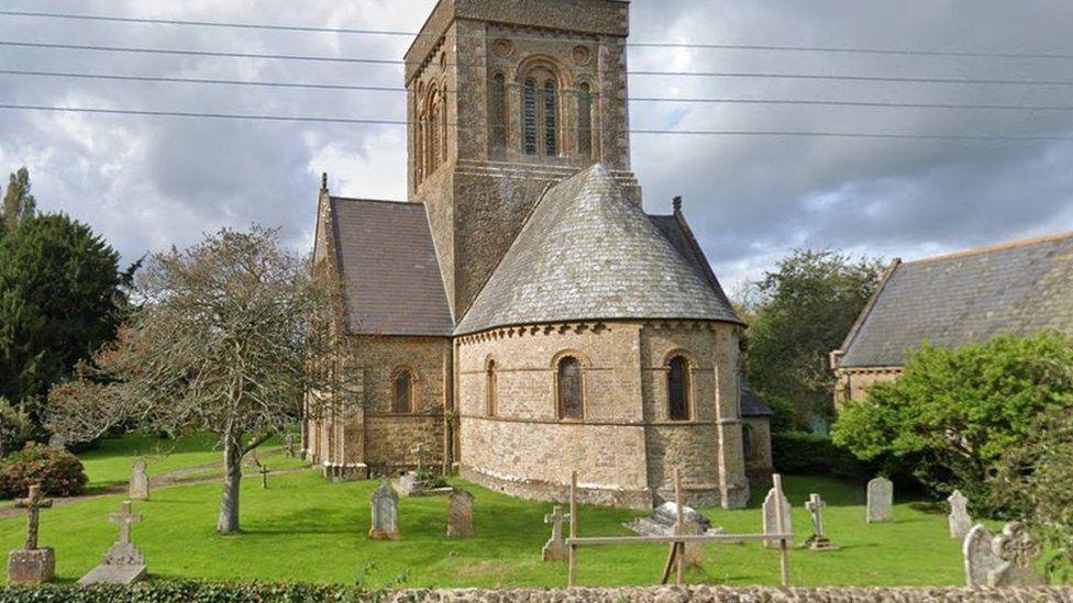 Pale stone church with grassed graveyard surrounding the building.