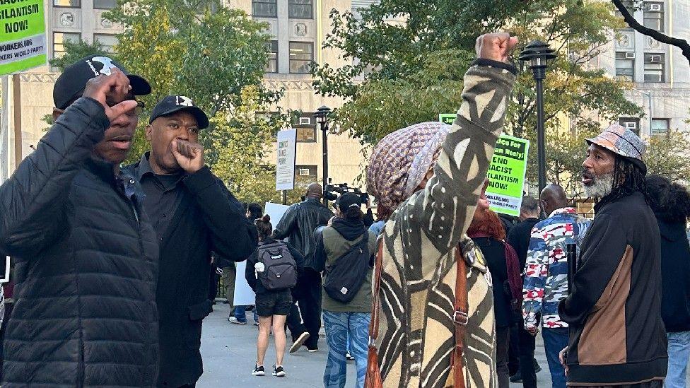 A group of protesters, some with their fists in the air, gather outside the courthouse in New York City