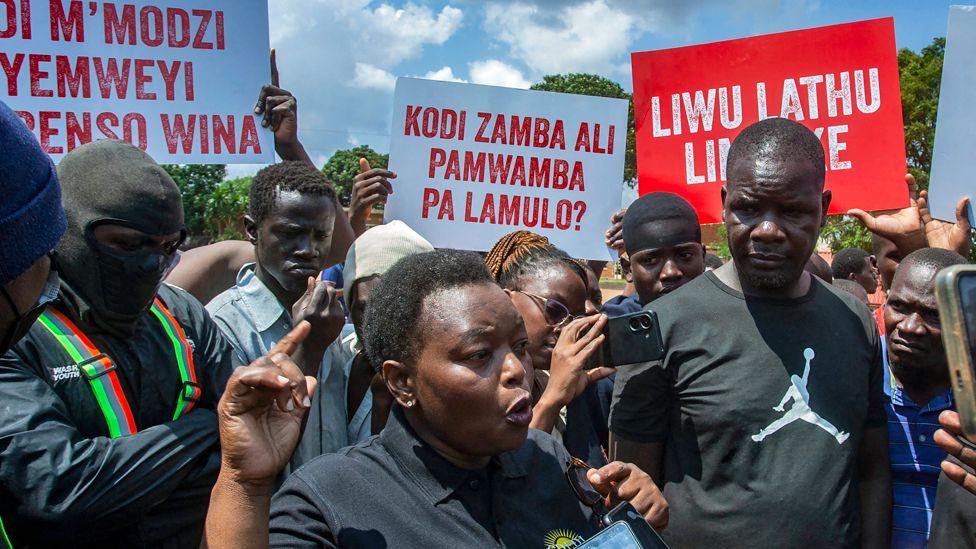 A demonstrator in a crowd of protesters at Lilongwe community ground, talks to journalists about why they are angry about the scarcity of fuel in Malawi - November 2024.