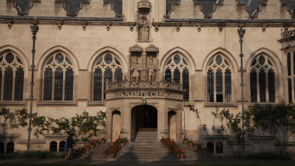 Oriel College as viewed from the front quad. Steps lead up to the entrance. 'Regnante Carolo' is carved on the parapet. Statues adorn the building above.