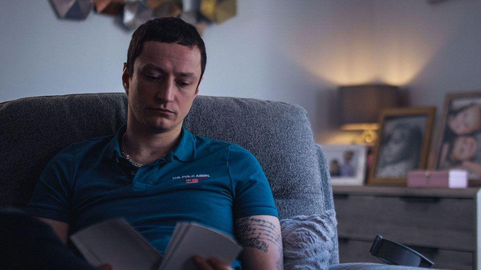 Scott Peden sitting on a chair looking at images of his family