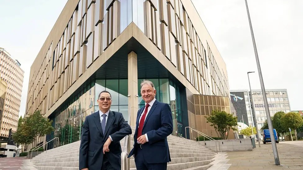 Charles Huang and Prof Sir Jim McDonald, the university's principal and vice-chancellor, stand in front of the steps leading to a university building. 