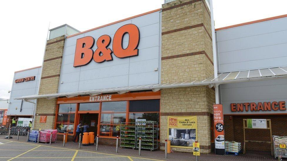 The exterior of a large B&Q store. The company's name is in bright orange letters on the front of the building, above the entrance.