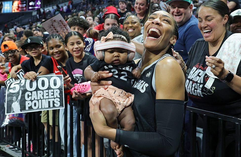A'ja Wilson of the Las Vegas Aces poses for photos with a fan's baby wearing her jersey in Las Vegas. Wilson became the quickest and youngest player in WNBA history to score 5000 career points. Photo by Ethan Miller