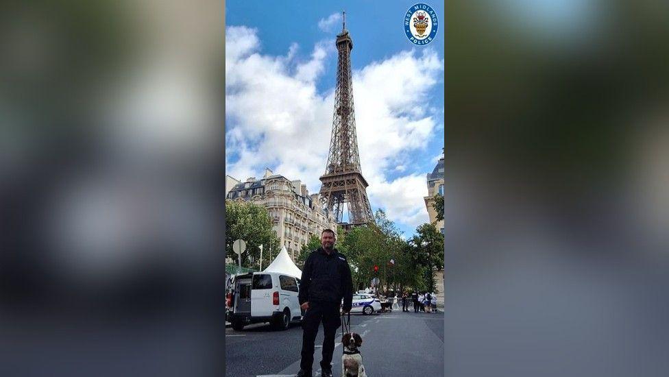 A uniformed officer and a police dog stood outside the Eiffel Tower