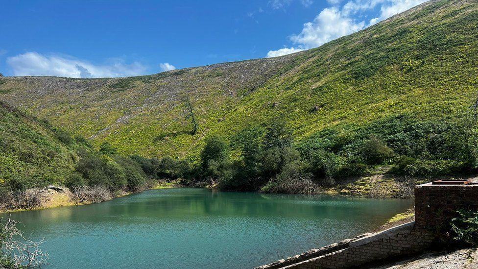 Brombil Reservoir is a blue lakes surrounded by steep green hills