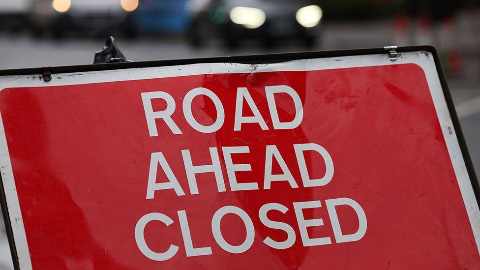 A street sign that says 'road closed' in white capitals on a red background