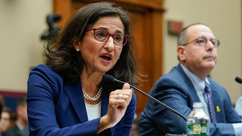 Minouche Shafik gestures as she talks into a microphone 