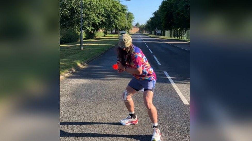 Man dressed in colourful running gear and false beard standing in road