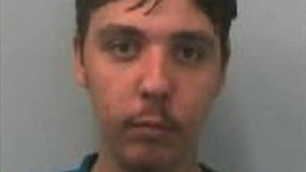 A mugshot of Jason Conroy. He has brown hair and is looking directly at the camera