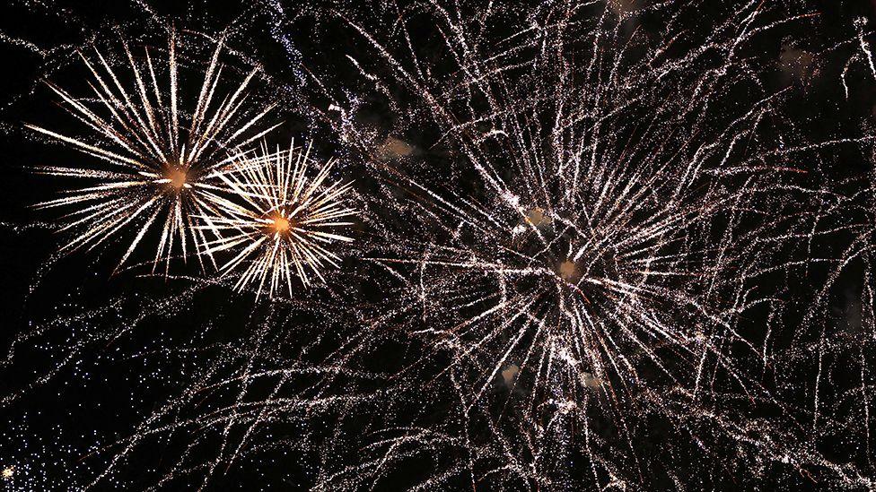 A generic picture of white fireworks exploding in the night sky