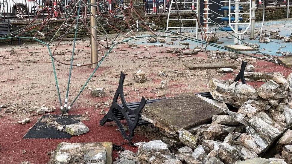 Rubble and overturned benches amid a play area.