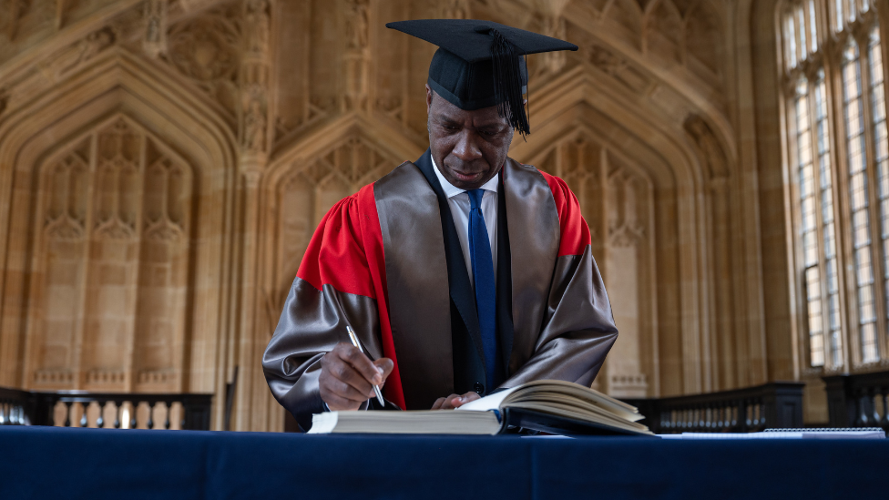 Clive Myrie signs a book during Oxford University's annual Encaenia Ceremony, where award honorary degrees are awarded.