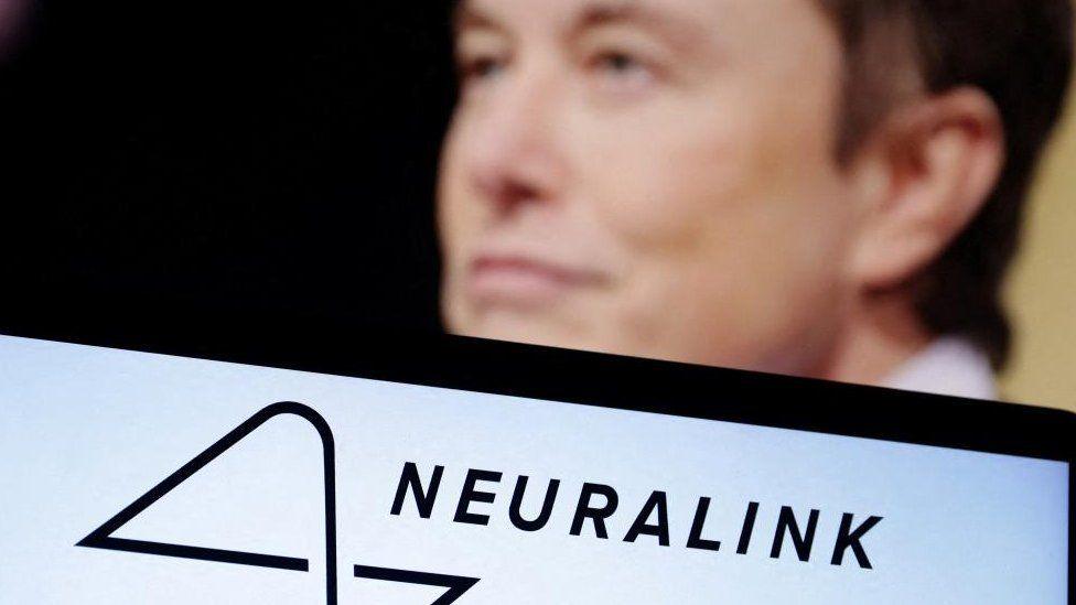 Sign for 'Neuralink' with Elon Musk standing in the background 