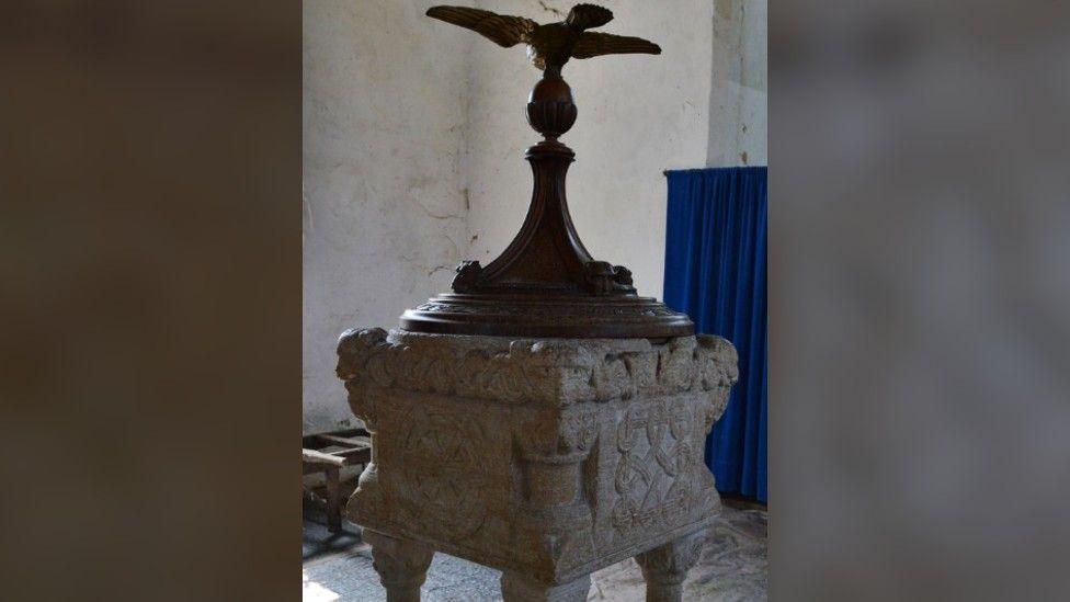 The Norman font inside the All Saints church in Toftrees.