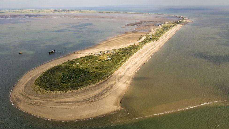 Aerial view of Spurn Point a thin peninsula of land at the mouth of the Humber Estuary surrounded by sand with a few buildings in the middle