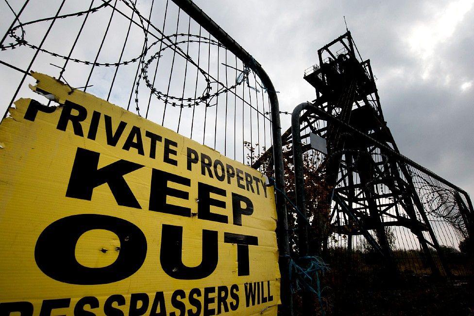 Mine winding gear with a keep out sign, fencing and barbed wire in front of it