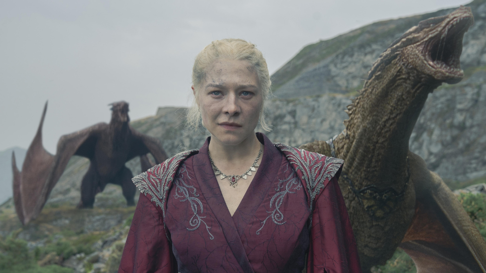 Woman in red period style dress with red dragons beside her and in background