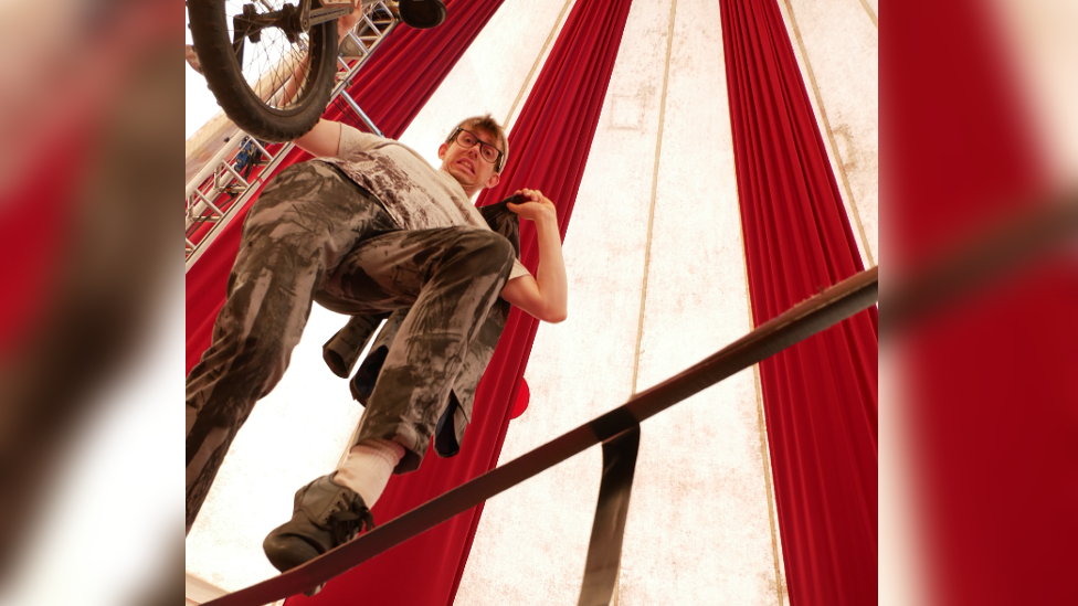 Sam Goodburn on top of a unicycle inside a circus tent