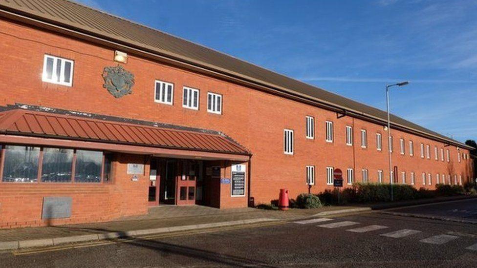 Two-storey brick cell block with small windows and adjacent road with zebra crossing