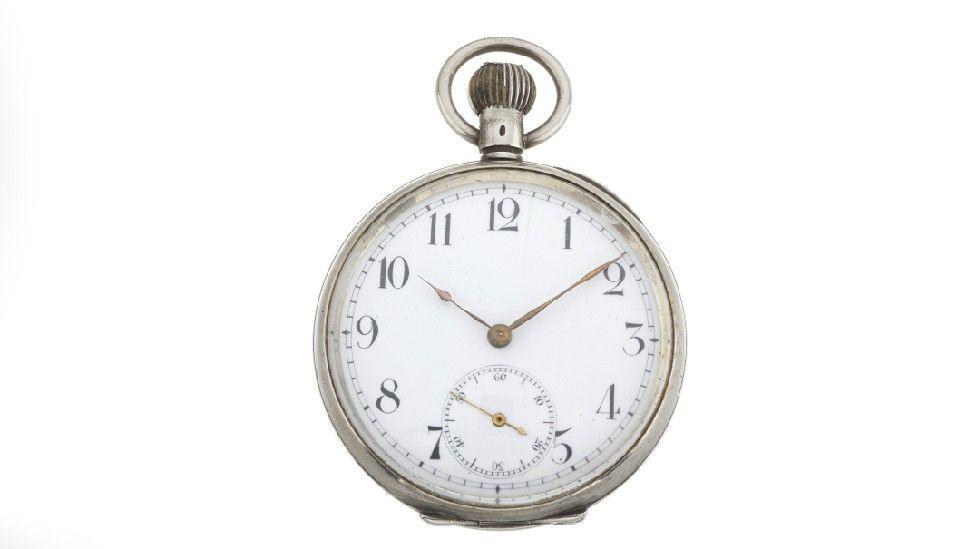 A silver pocket watch with black numbering against a white background. The time on the pocket watch reads 10 past 10.