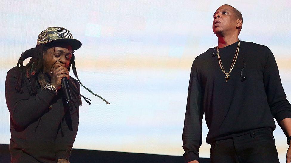 Lil Wayne and Jay-Z, both dressed in black, performing together on stage