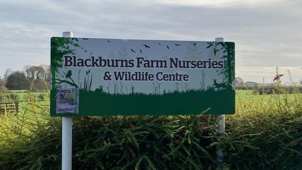 A sign in a field saying Blackburns Farm Nurseries and Wildlife Centre