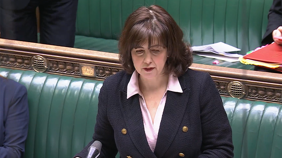 Lucy Powell addressing the House of Commons. She is wearing a blue jacket and the green benches of the Commons are in the background 