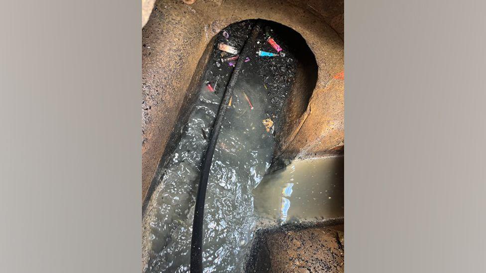 Sludge and vapes being dislodged from a sewer pipe.  