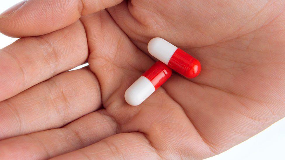 Two red and white tablets in a hand