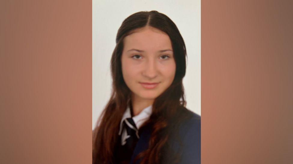 Scarlett in her school uniform with her long brown hair on her shoulders