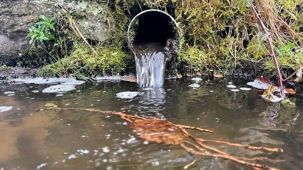 Raw sewage flowing from a pipe into a river