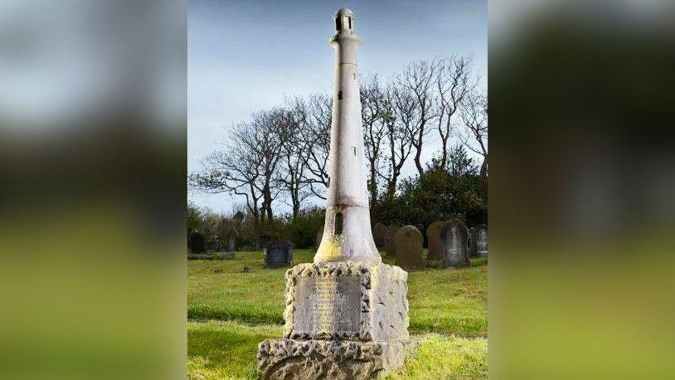 The monument to James Gall and Grace Darling located in Barrow Cemetery. It is shaped like a small lighthouse and features steps leading to a doorway.