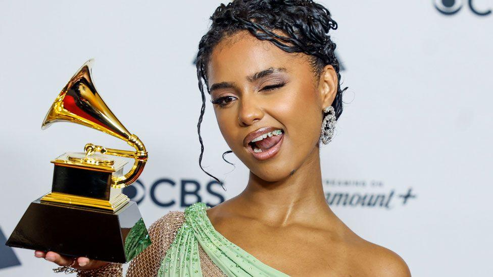 Tyla holding her Grammy Award in Februay 2024 winks for photographers