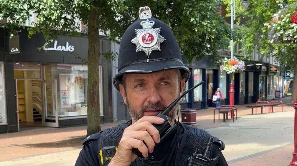 PC Phil Smith in uniform holding a walkie talkie