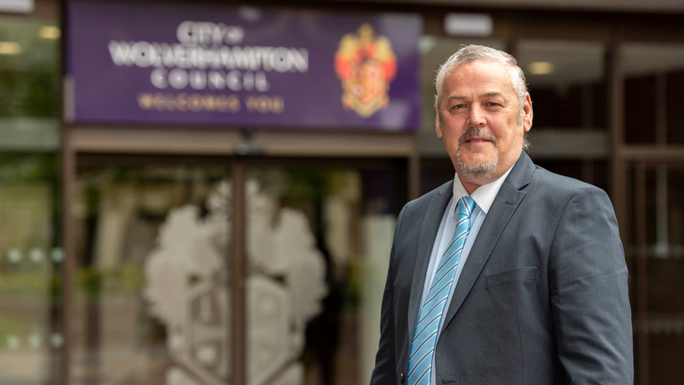 Ian Brookfield, wearing a grey suit jacket and a blue tie, stands outside the civic centre in Wolverhampton