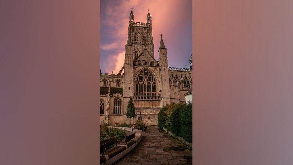 Gloucester Cathedral in front of a pink sky.