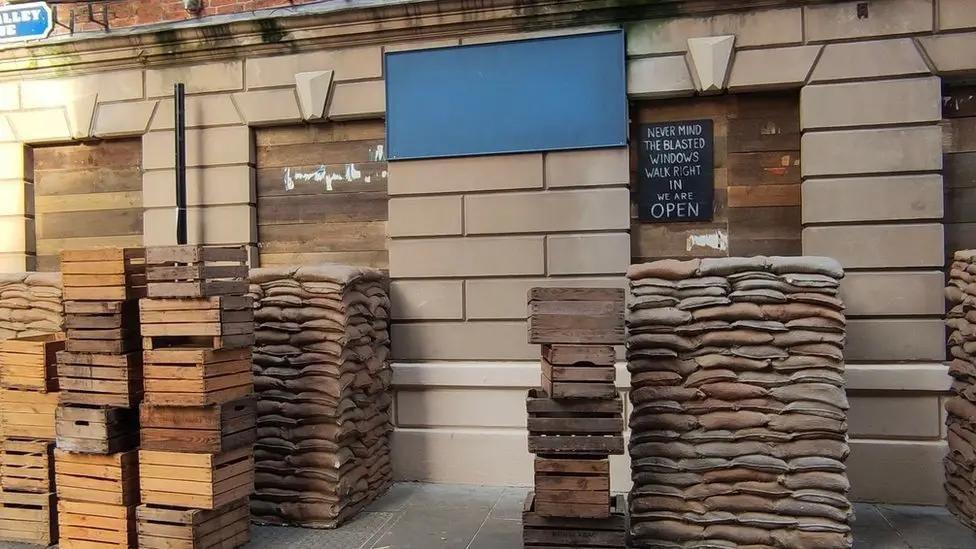 A building in Hull's Old Town has been obscured by sandbags, wooden crates and boarded up windows as part of a film set.