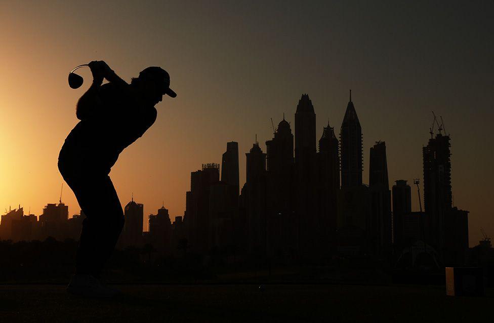 France's Romain Langasque tees off during his opening round at the Dubai Desert Classic, silhouetted against the city's skyline. Photo by Andrew Redington