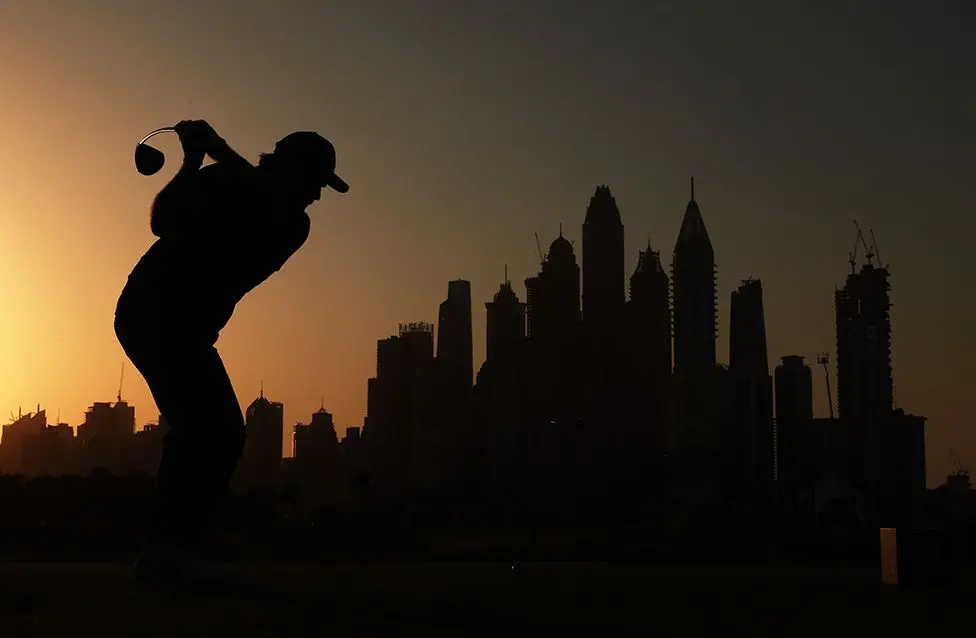 France's Romain Langasque tees off during his opening round at the Dubai Desert Classic, silhouetted against the city's skyline. Photo by Andrew Redington